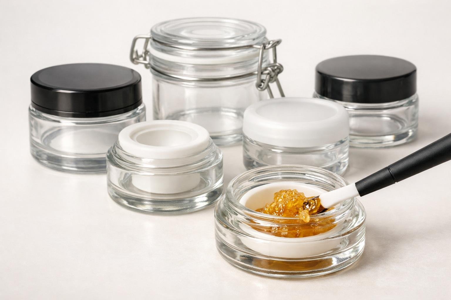 How to Prevent Concentrates From Sticking to Glass Jars: Expert Storage Guide 2 A collection of glass jars with airtight lids and a silicone spatula scraping concentrate from one jar.